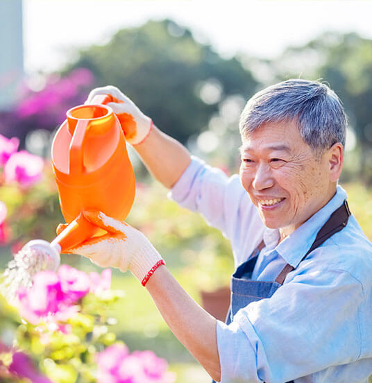 Elderly man watering flowers